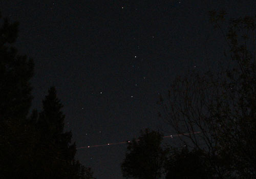 close up of Comet Holmes with an airplane flying under it